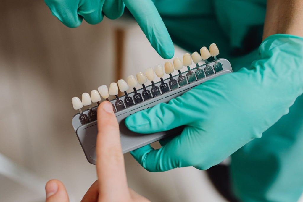 A dentist pointing to a dental crown model while explaining the procedure to a patient